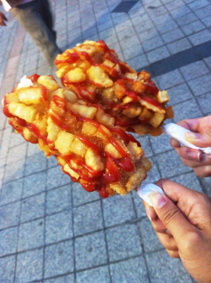 Korean corn dog coated with french fries and crispy batter on a stick